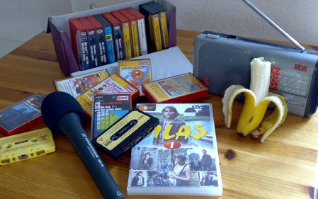 Mein alter Kassettenkoffer, ein kleines Radio, eine Silas-DVD, ein Mikrofon und eine angebissene Banane